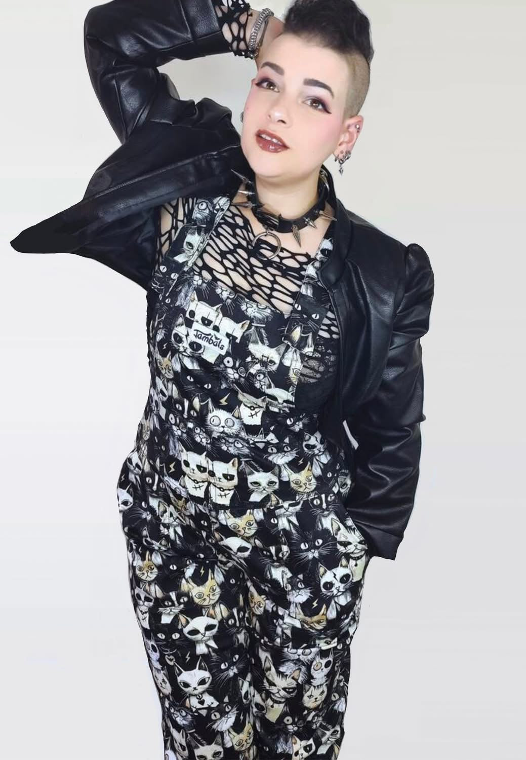 Model wearing black and white dungarees with a print of cute but gothic punk alley cats. Alternative cats print overalls. 