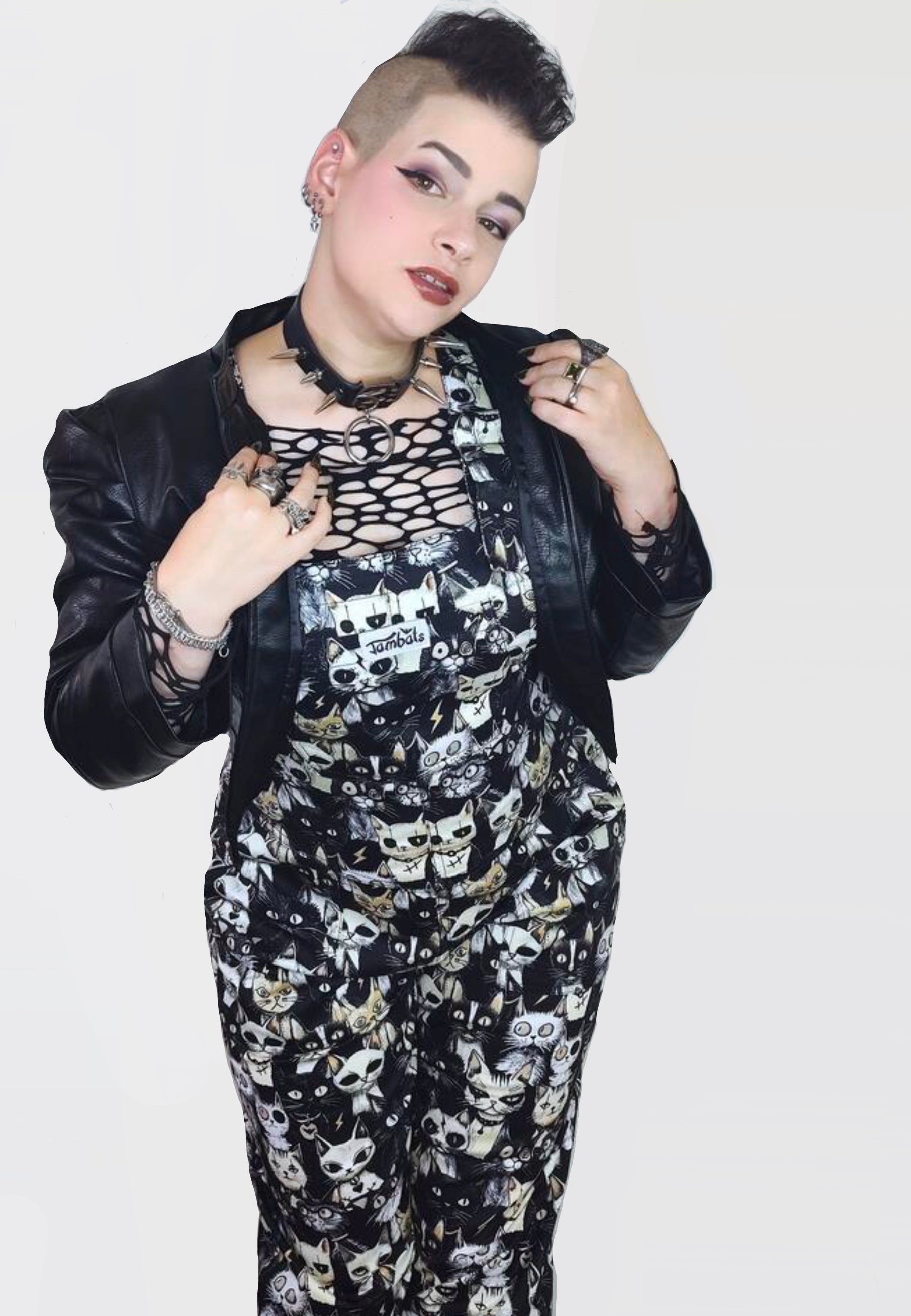 Model wearing black and white dungarees with a print of cute but gothic punk alley cats. Alternative cats print overalls. 