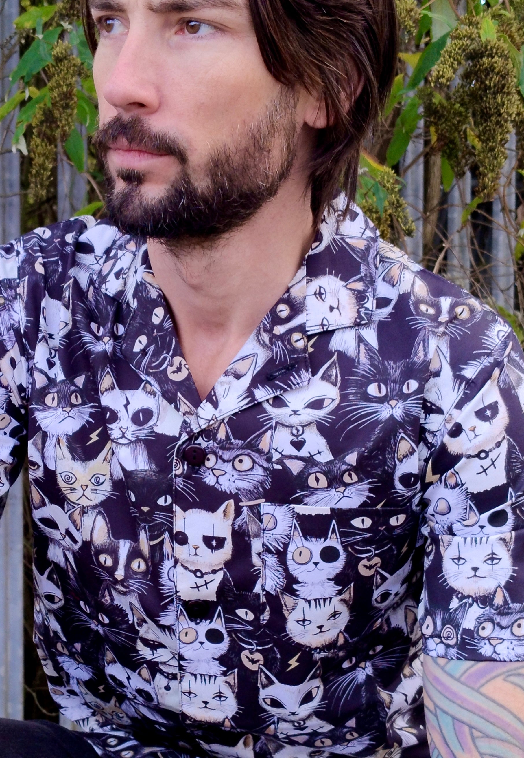 Man wearing a shirt with a print of quirky gothic cats. Close up photo of the shirt details