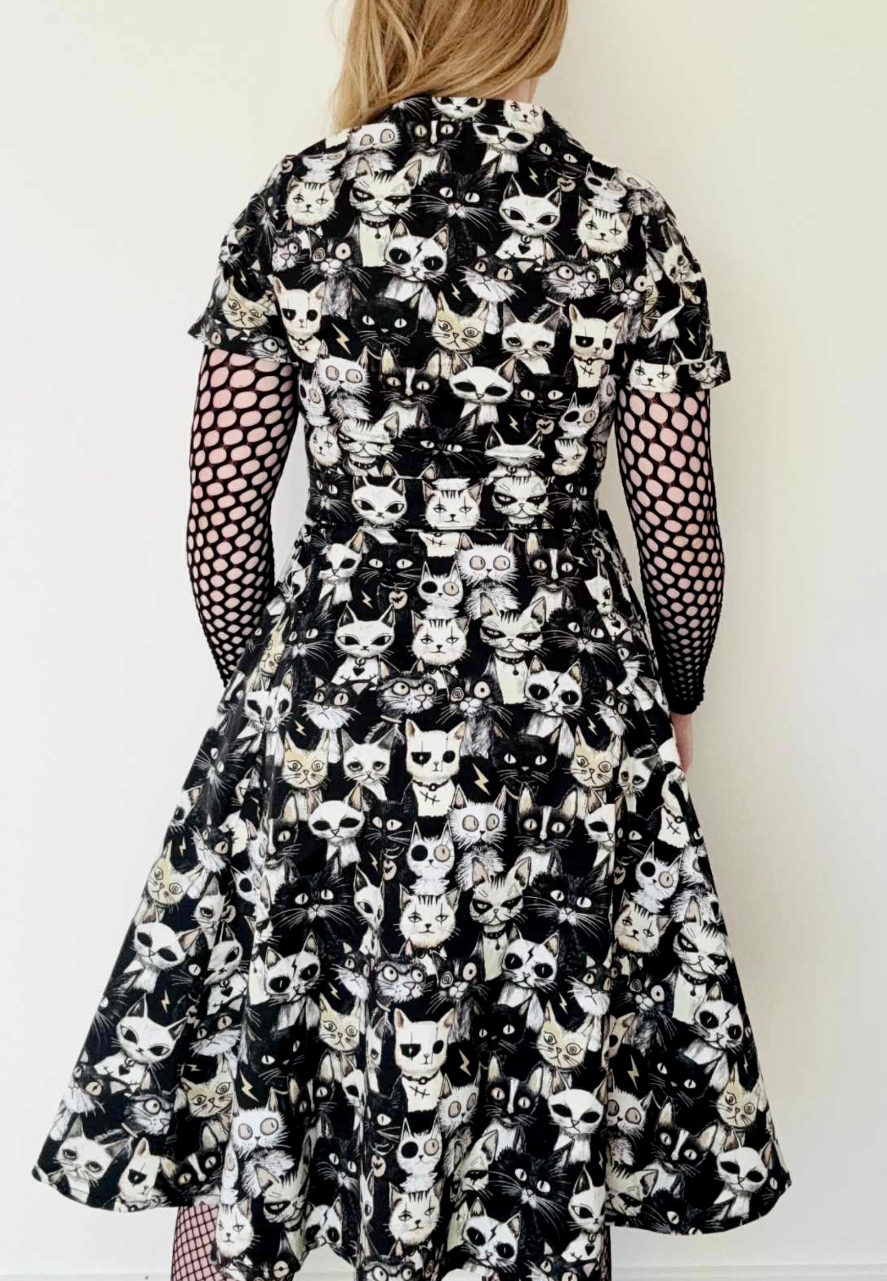 Black view of an alternative style shirt dress with a quirky Alley Cats pattern worn by a woman against a white background