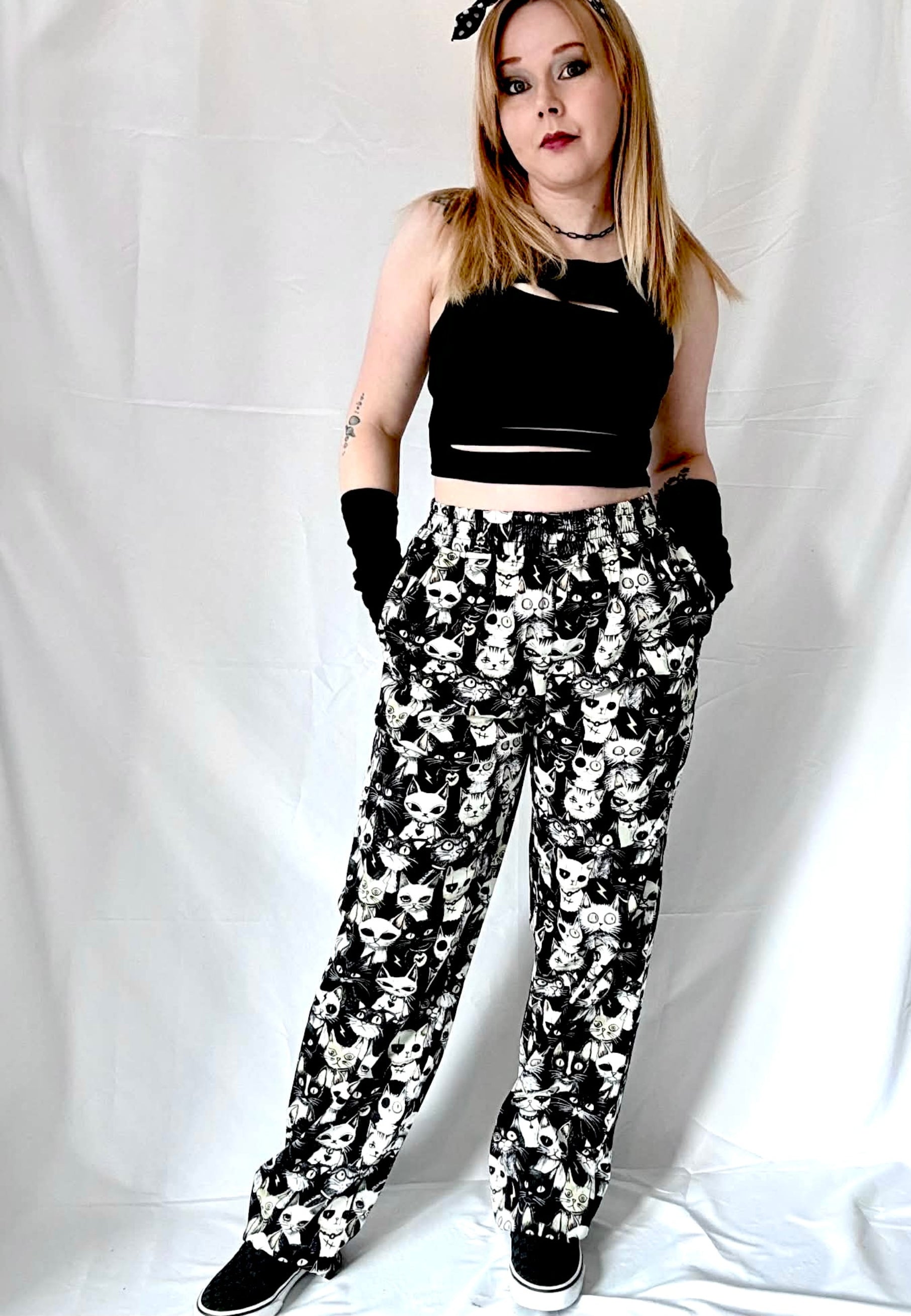 Person wearing a black crop top and gothic cats trousers on a white background. Retro hair tie styling. 