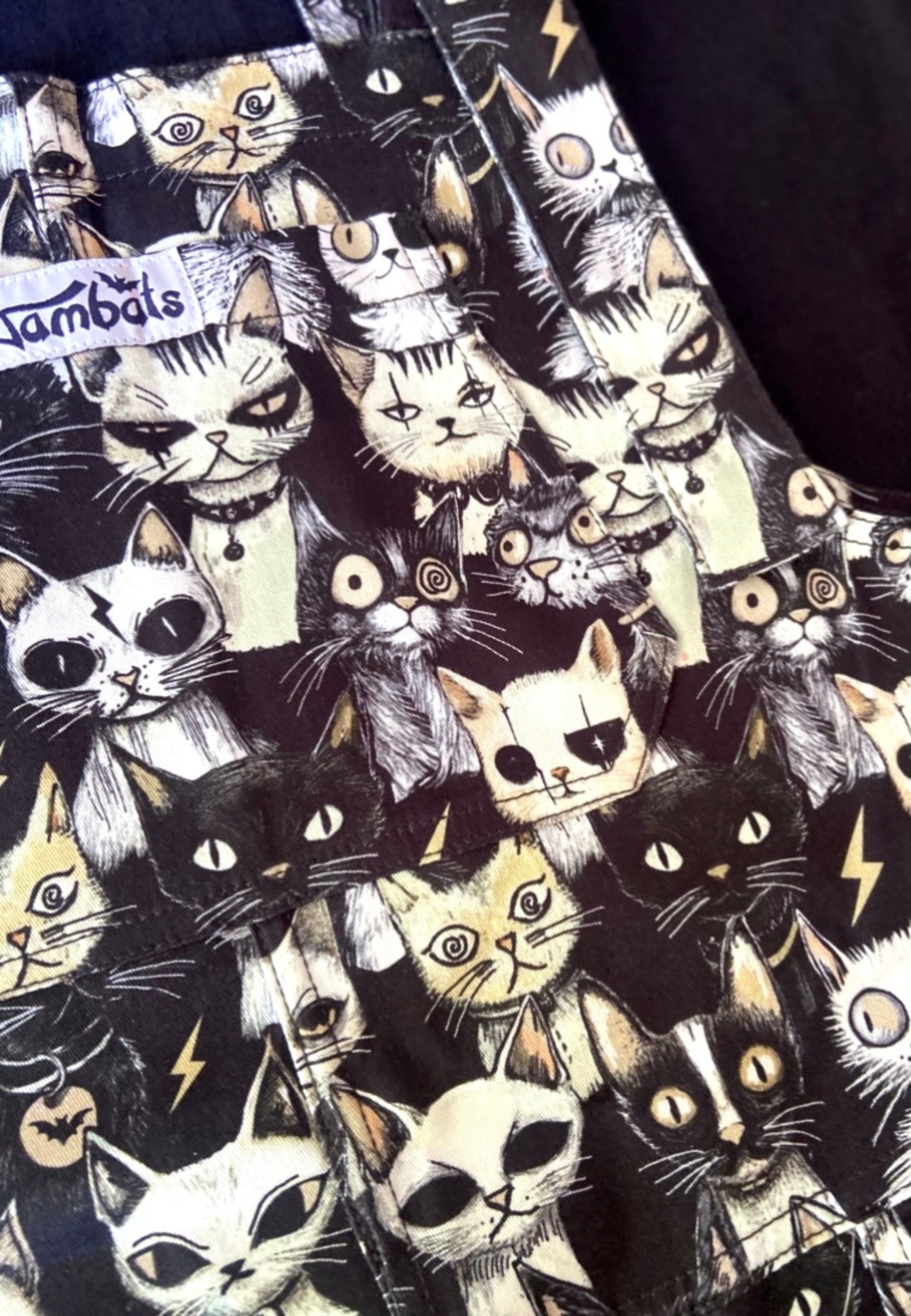 Close up of Jambats Alley Cats dungarees. Showing the quirky print of gothic punky alley cats. 
