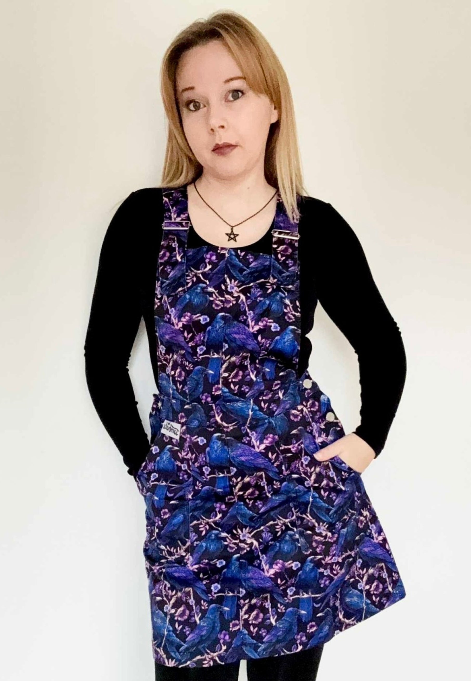 Woman wearing a pinafore with a beautiful print of Corvids, crows and ravens. Studio photo 