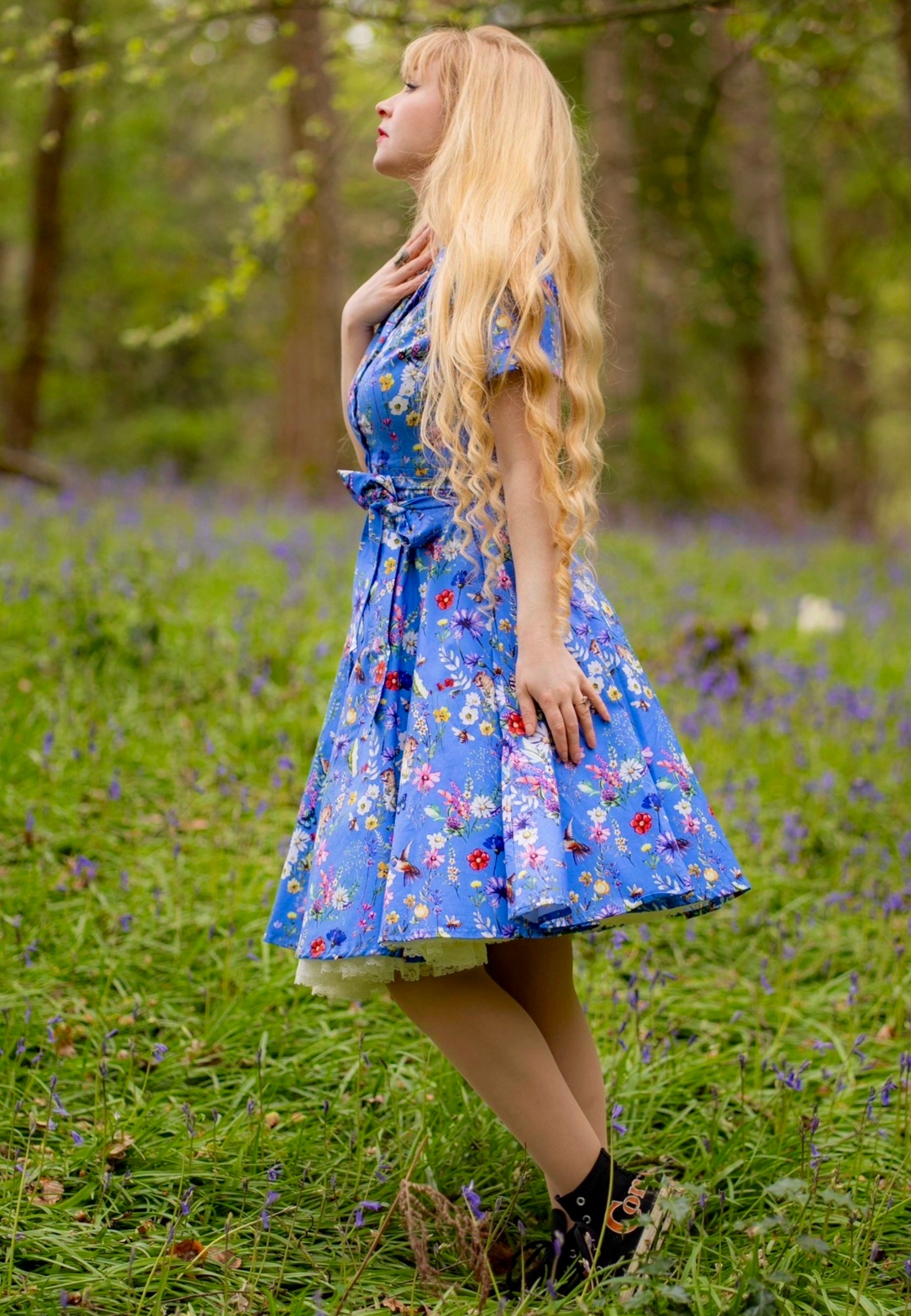 Woman in a beautiful blue floral dress standing in a field of flowers