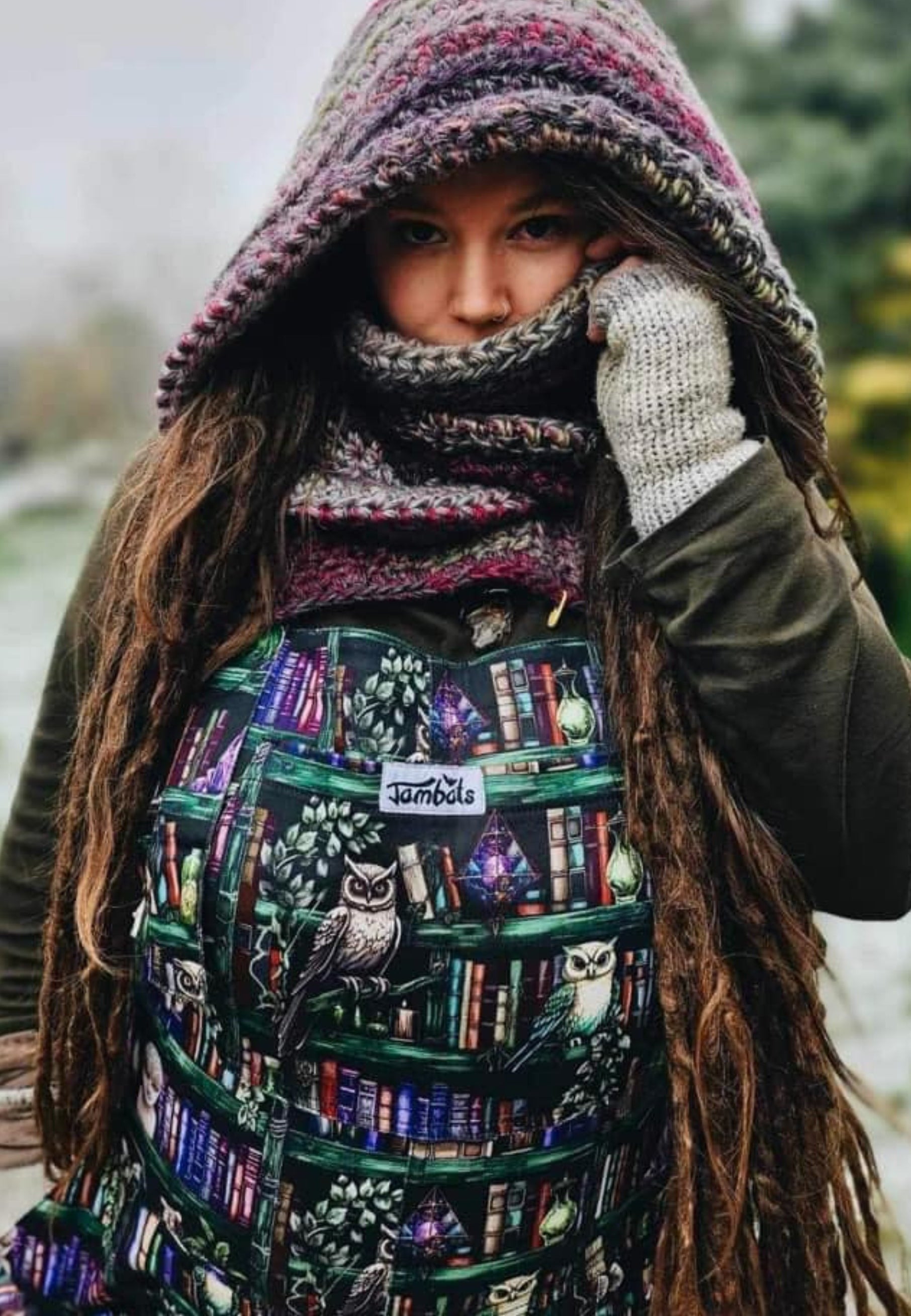 A woman wearing cotton twill dungarees with a unique bookcase and wise owls  print, standing outdoors.