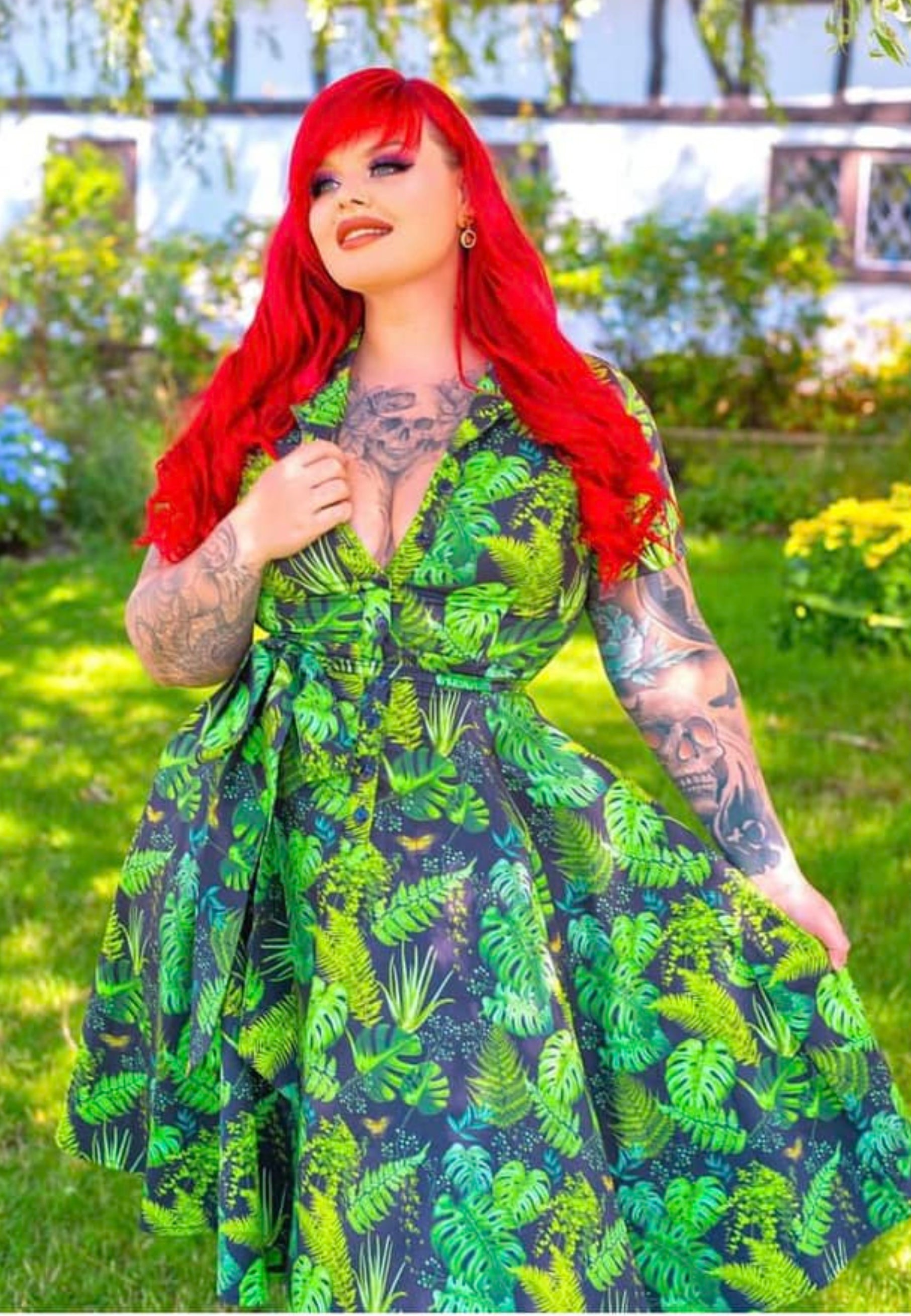 A woman with long red hair wearing a beautiful shirt shirt dress with a houseplant print, standing outdoors.
