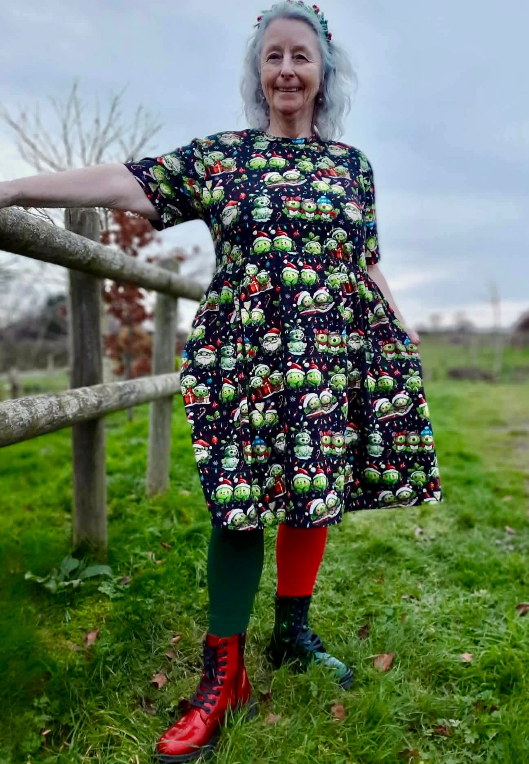 Woman wearing a colorful smock dress with a Christmas pattern of cute festive sprouts doing Christmassy stuff like car l singing, wrapping Christmas gifts, snowman sprout, Santa sprout, etc.