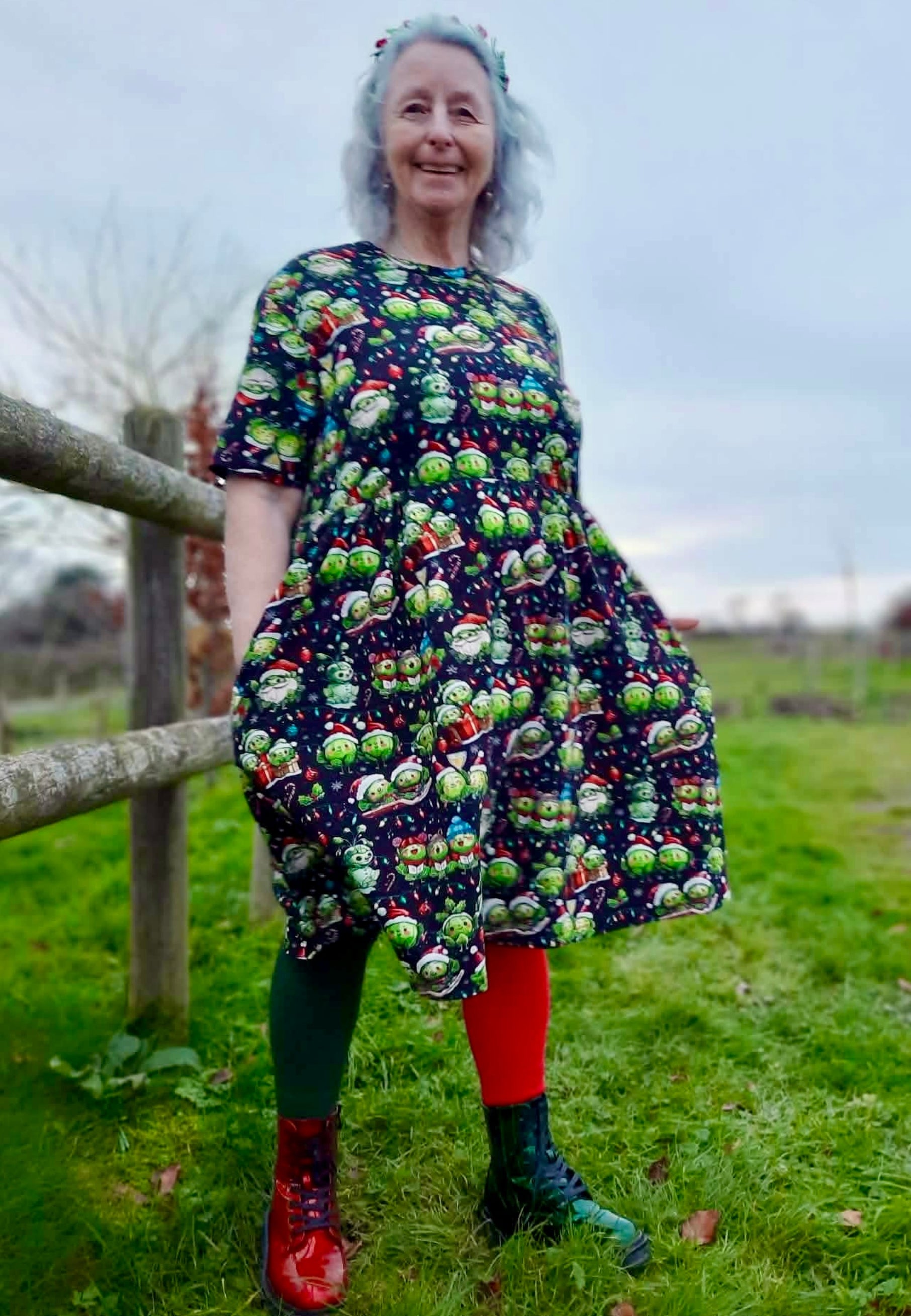 Woman wearing a colorful smock dress with a Christmas pattern of cute festive sprouts doing Christmassy stuff like car l singing, wrapping Christmas gifts, snowman sprout, Santa sprout, etc.