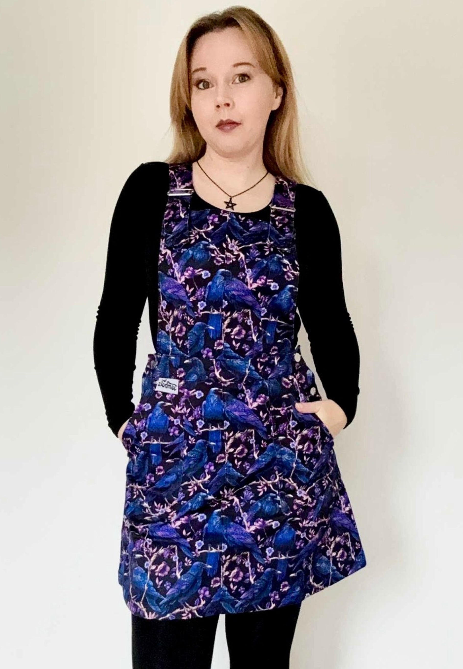Woman wearing a pinafore with a beautiful print of Corvids, crows and ravens. Studio photo 