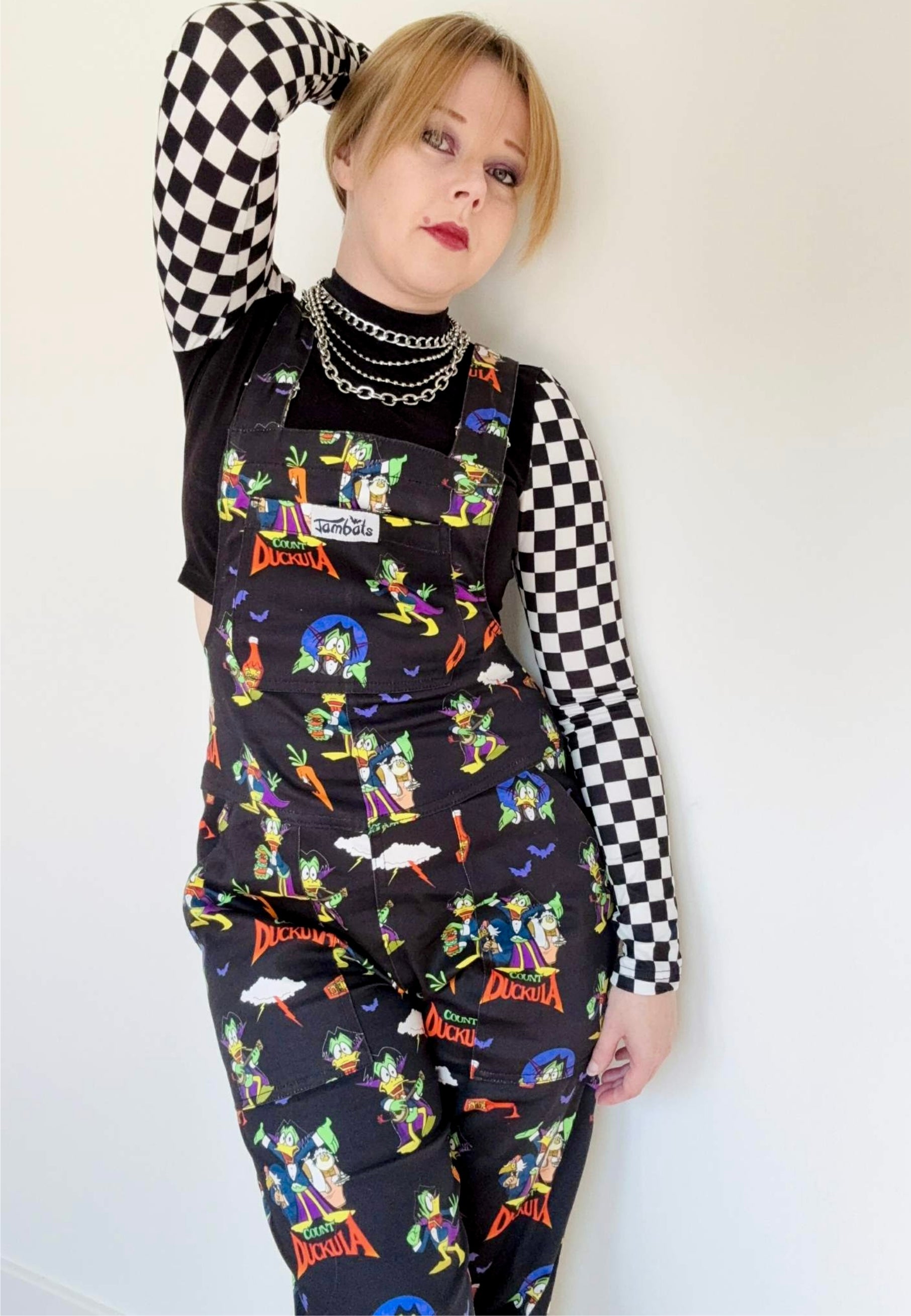 Woman wearing black Count Duckula print dungarees. Studio photo. 