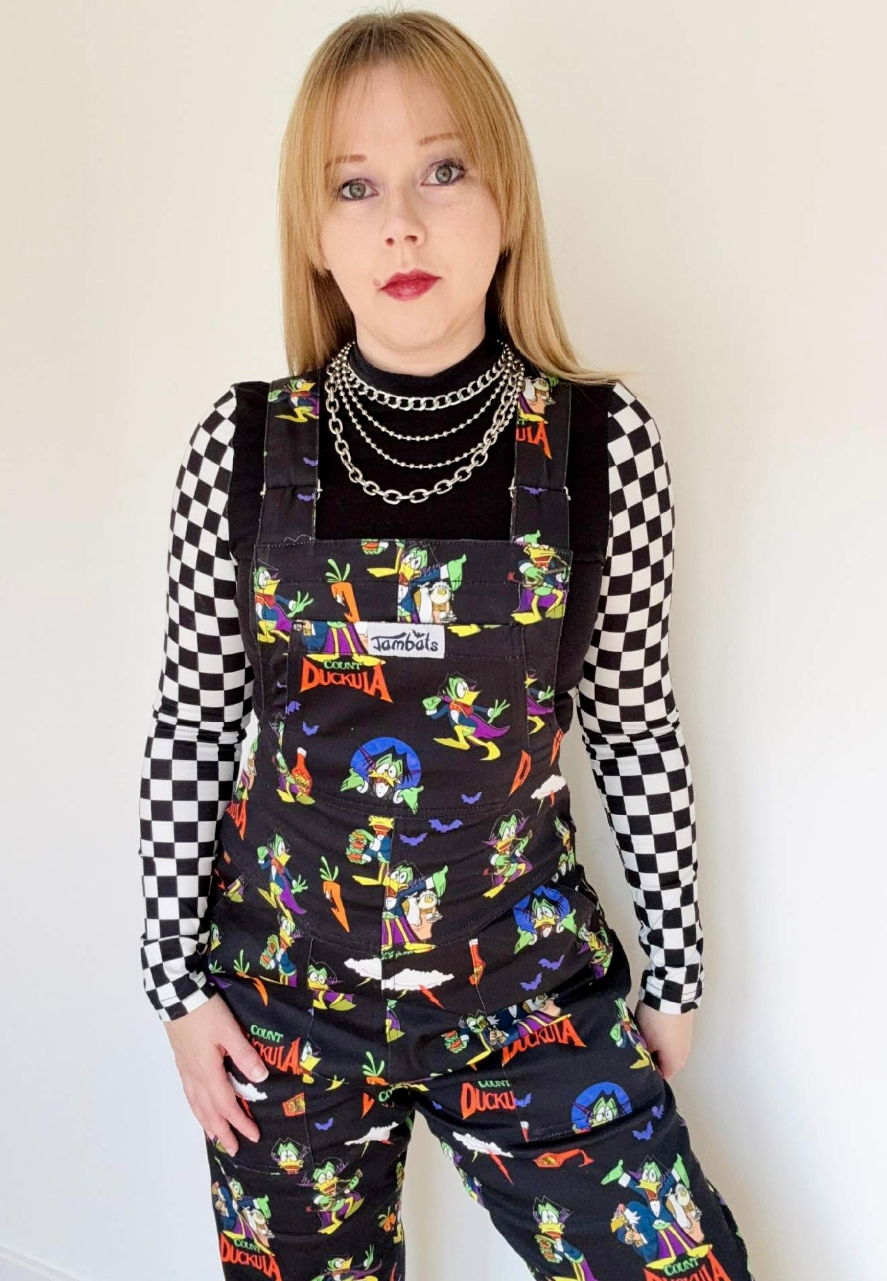 Woman wearing black Count Duckula print dungarees. Studio photo. 