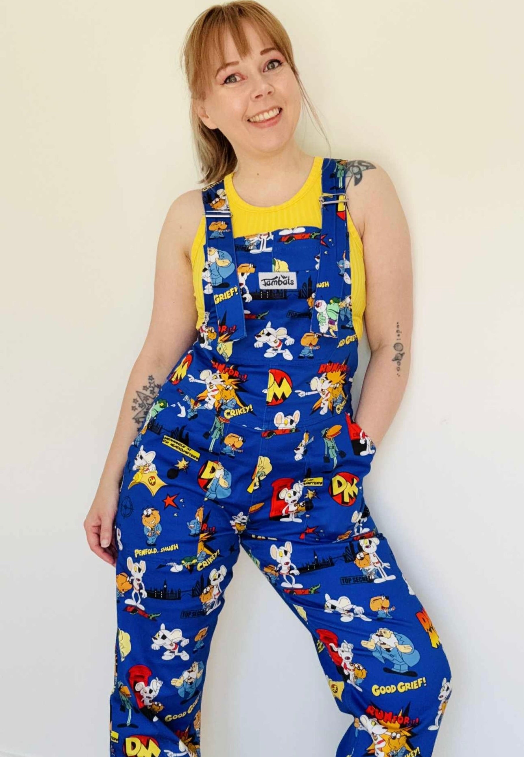 Woman wearing blue Danger Mouse dungarees with a yellow top underneath. Studio photo