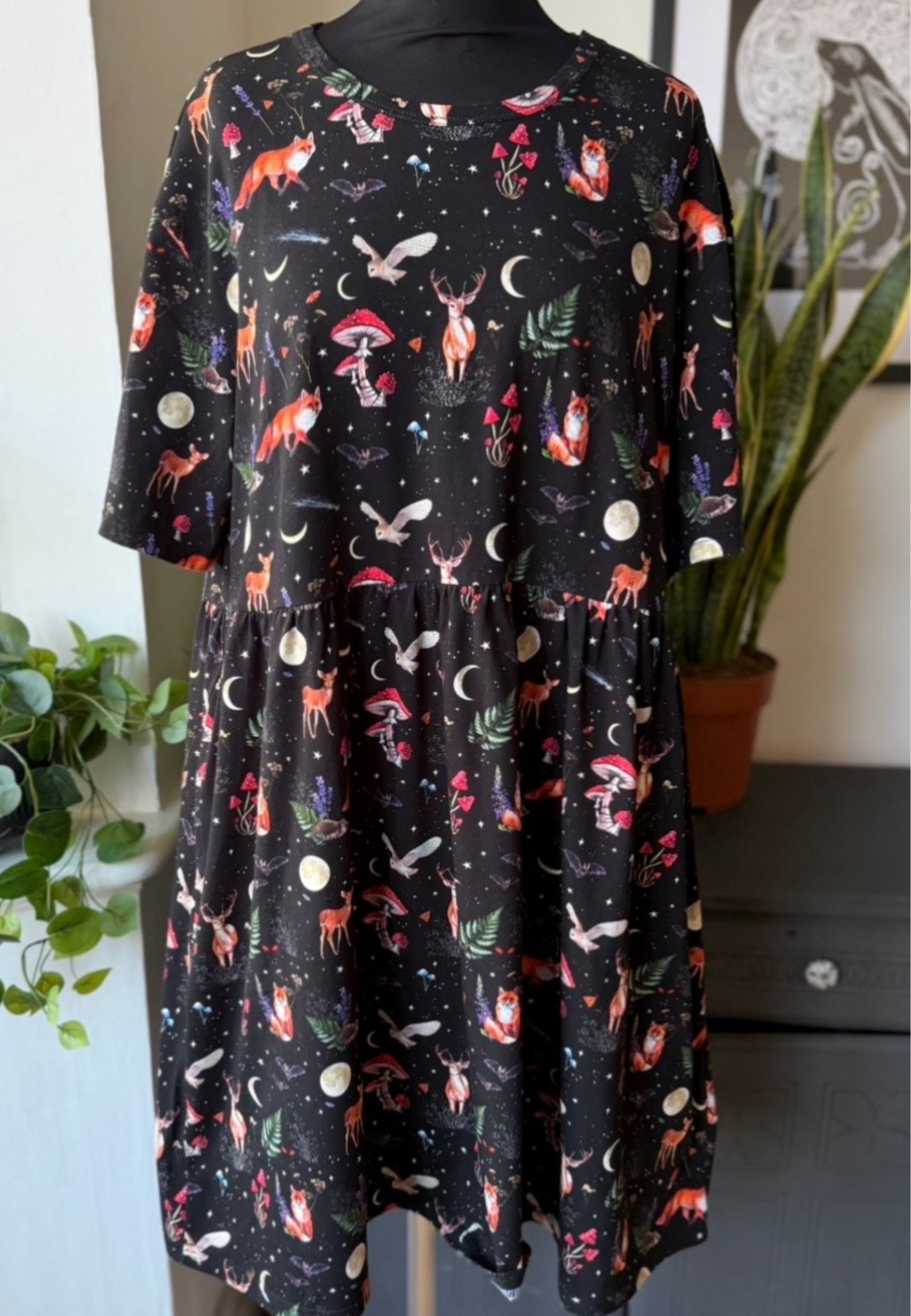 Black cottagecore smock dress with night forest print on a mannequin in a neutral setting. 