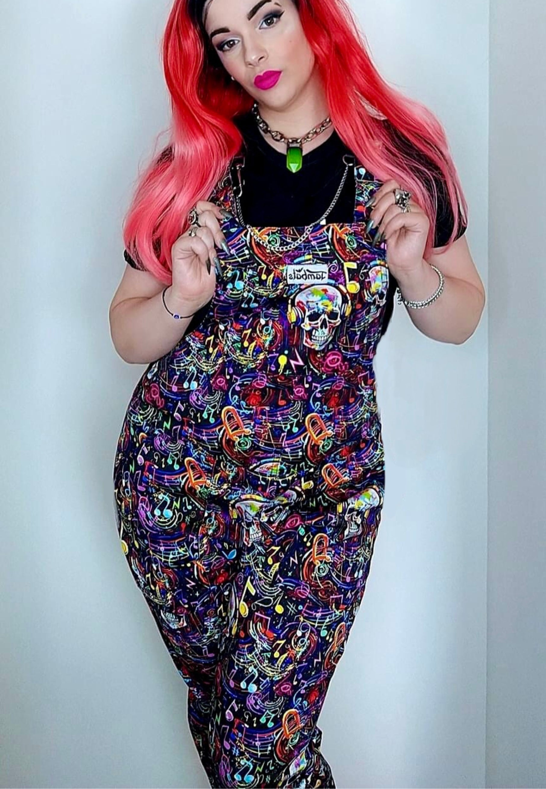 Woman wearing Graffiti Music Skulls Dungarees with long bright red hair. 80s 90s vibe.
