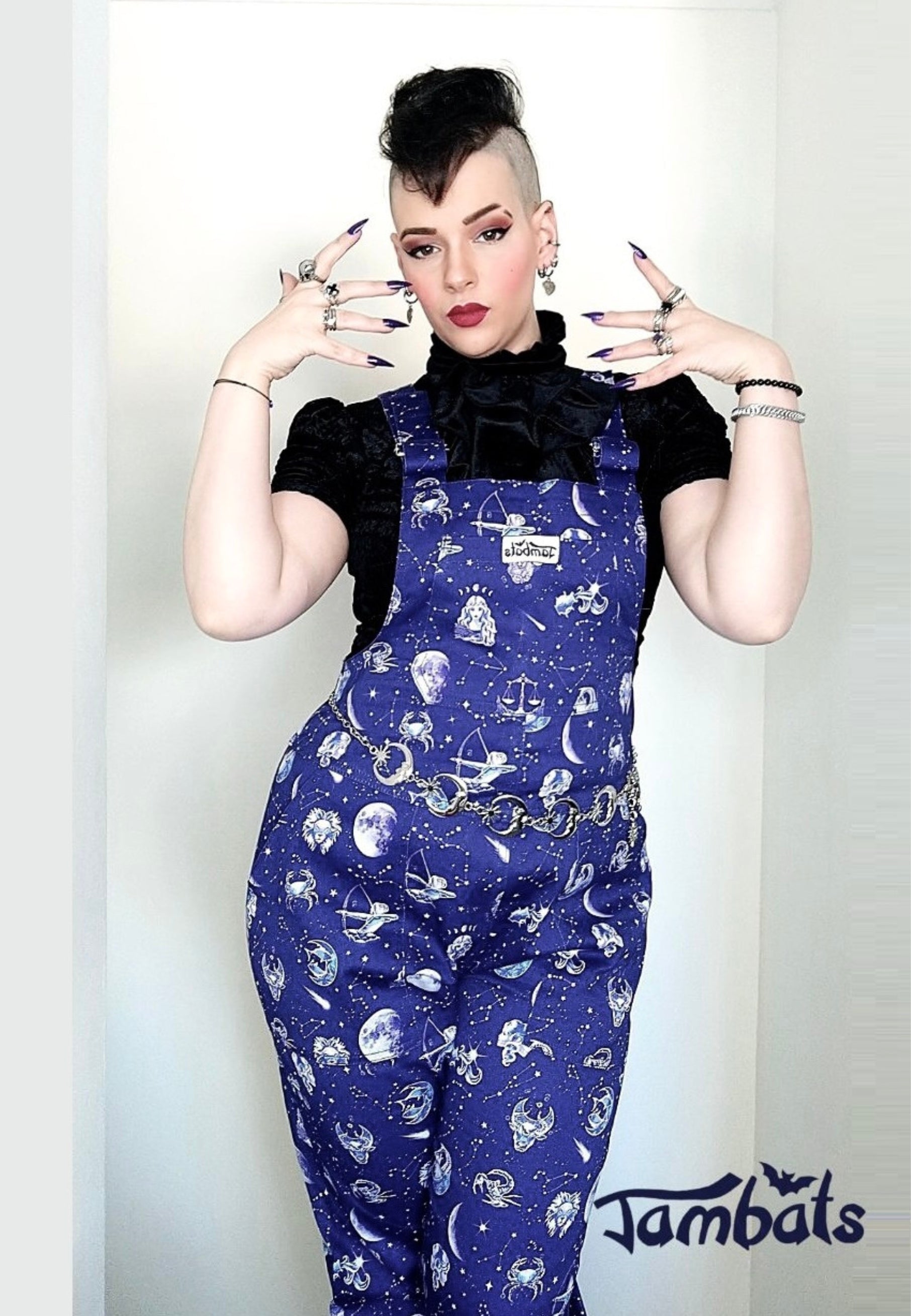 Woman wearing beautiful deep blue dungarees with a zodiac print. Celestial overalls. Jambats. 