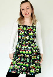 A woman wearing a festive pinafore dress with a pattern of Christmas sprouts. From carol singing to snowman building, Christmas partying to snow sledging… cheeky Sprouts celebrating the season. 