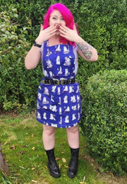 Woman wearing a beautiful blue pinafore with cute images of ghosts and ghost cats doing everyday things. Jambats January Sale. 