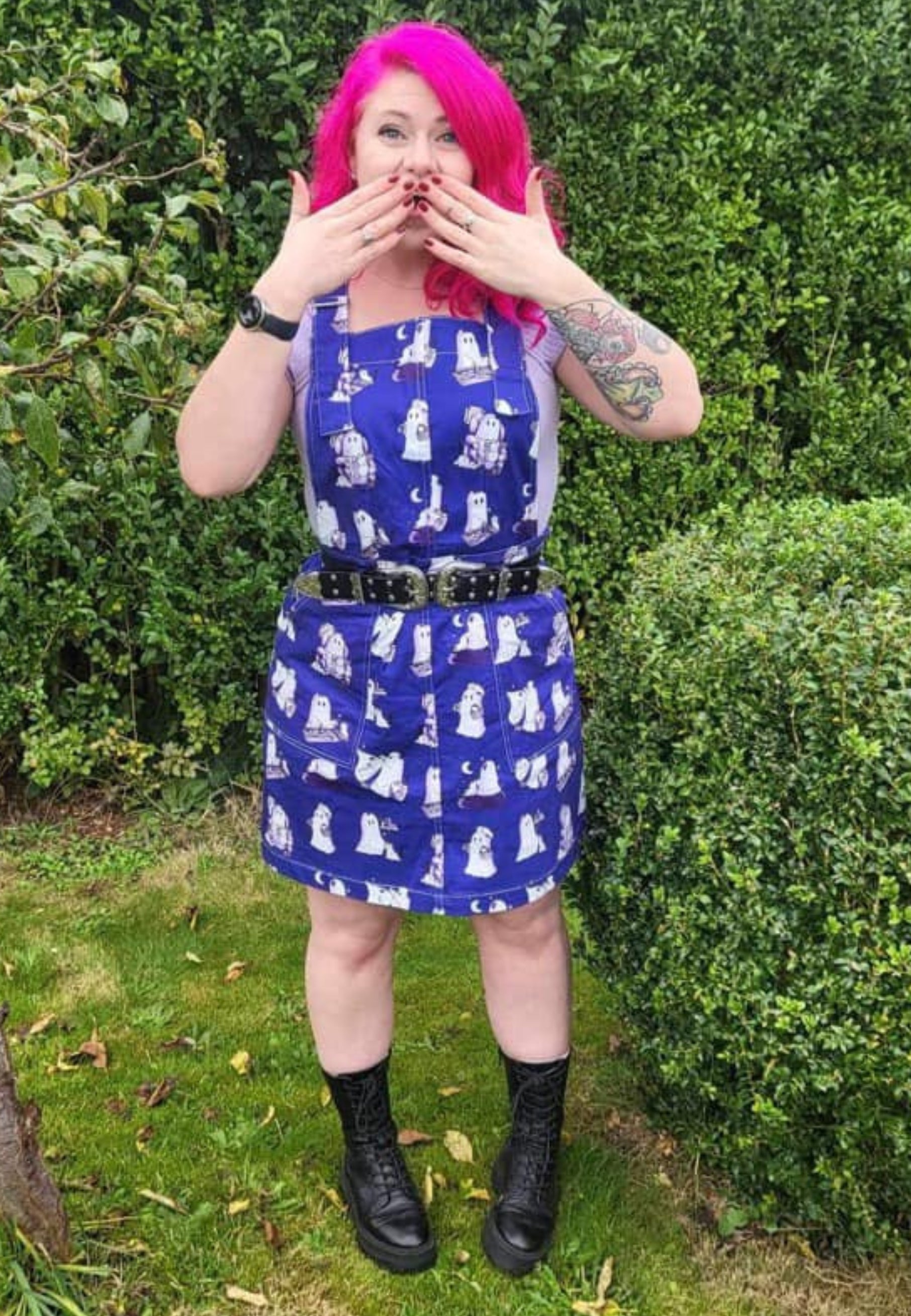 Woman wearing a beautiful blue pinafore with cute images of ghosts and ghost cats doing everyday things. Jambats January Sale. 