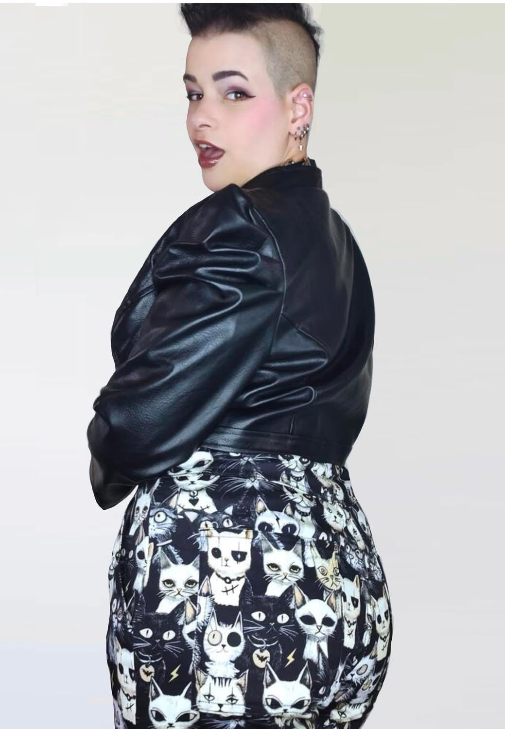 Back view of model wearing black and white dungarees with a print of cute but gothic punk alley cats. Alternative cats print overalls. 