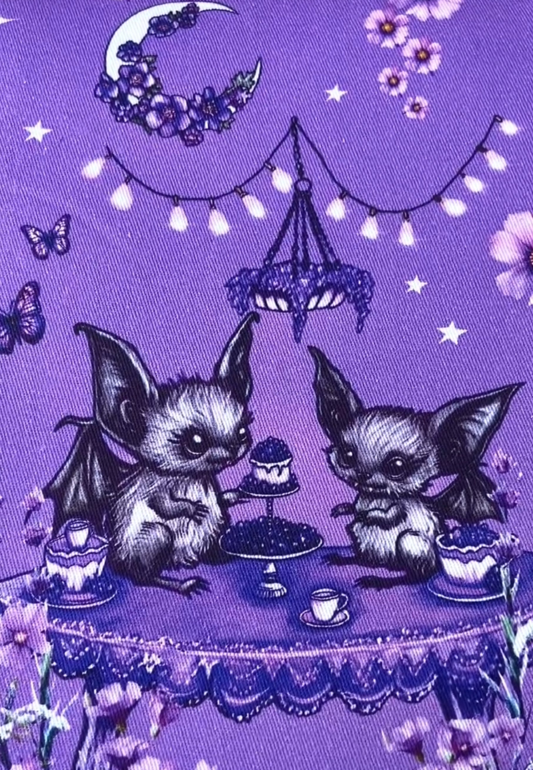 Close up of the detail in Jambats Bats Tea Party print. Purple deep lilac fabric with a whimsical hand illustrated of cute bats having a tea party under a floral moon. 