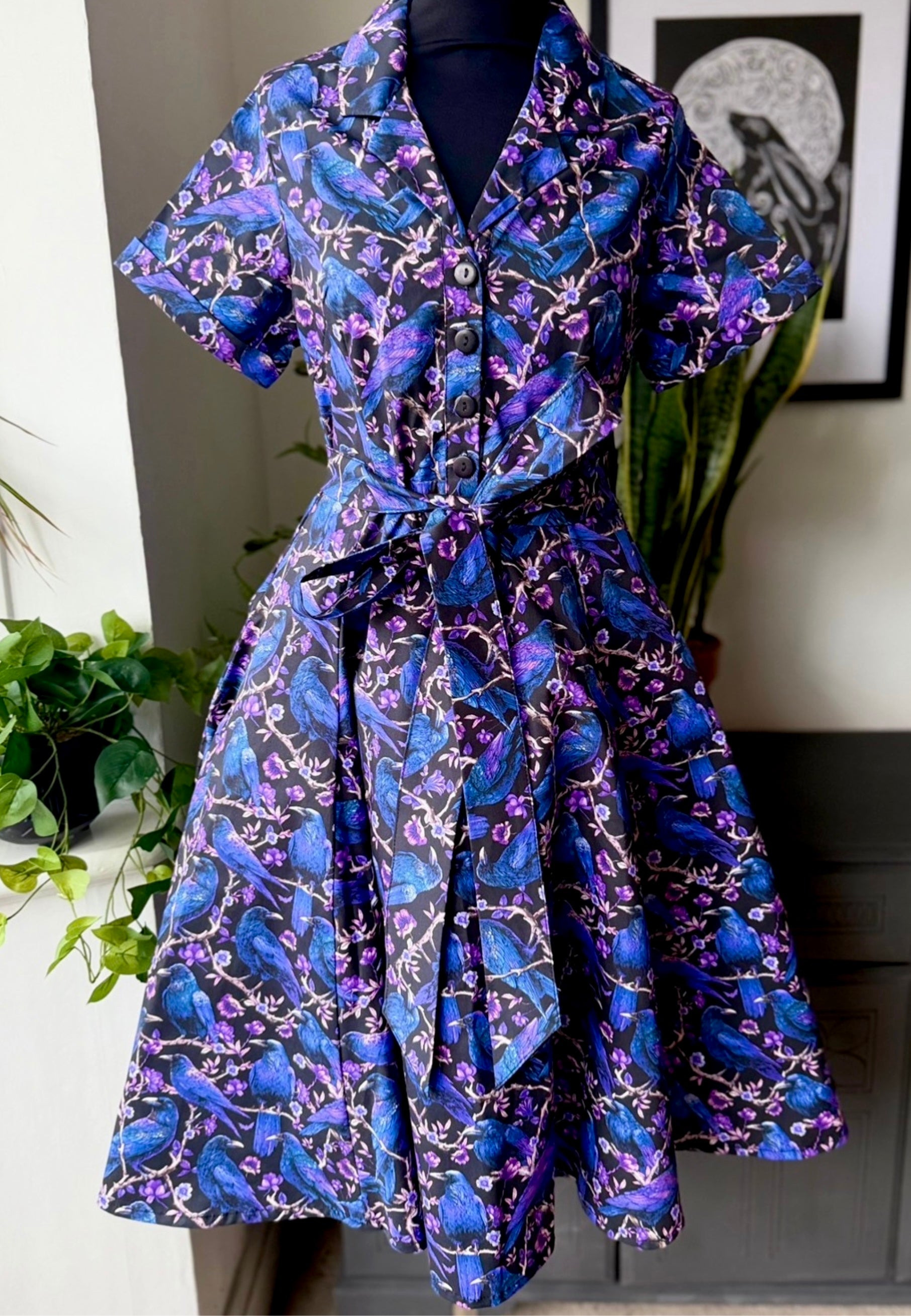 Shirt dress on a mannequin against a neutral background. Pattern on the dress is a beautiful print of ravens and crows.