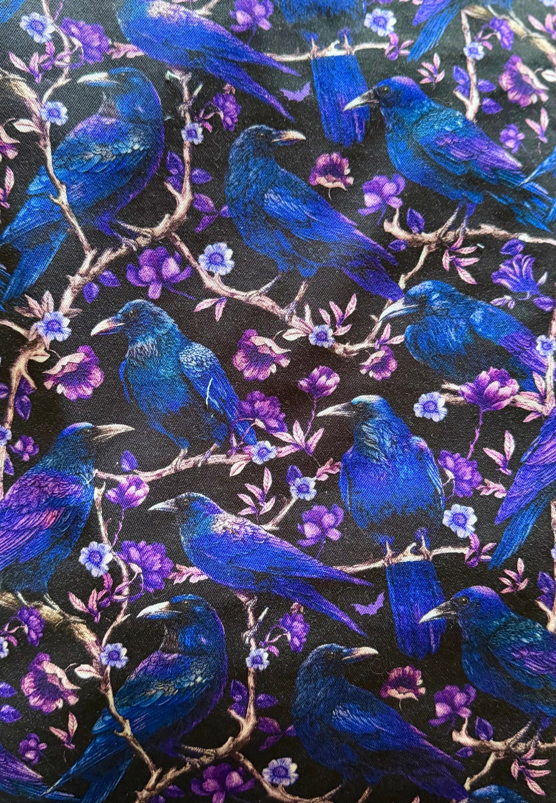 Pattern of blue cries and ravens and purple flowers on a black background