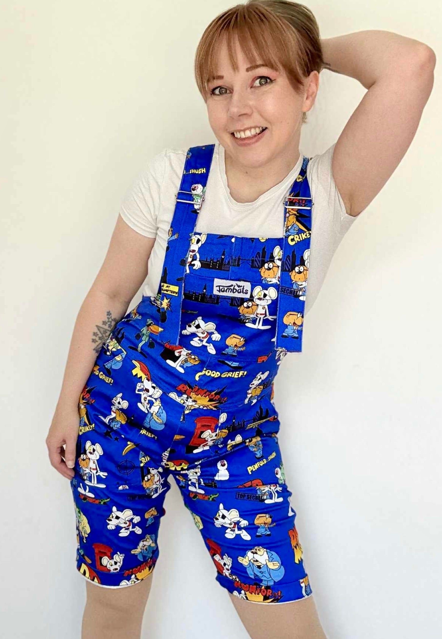 Woman wearing blue Jambats dungarees with the retro 80s cartoon characters DangerMouse on the print. Officially licensed