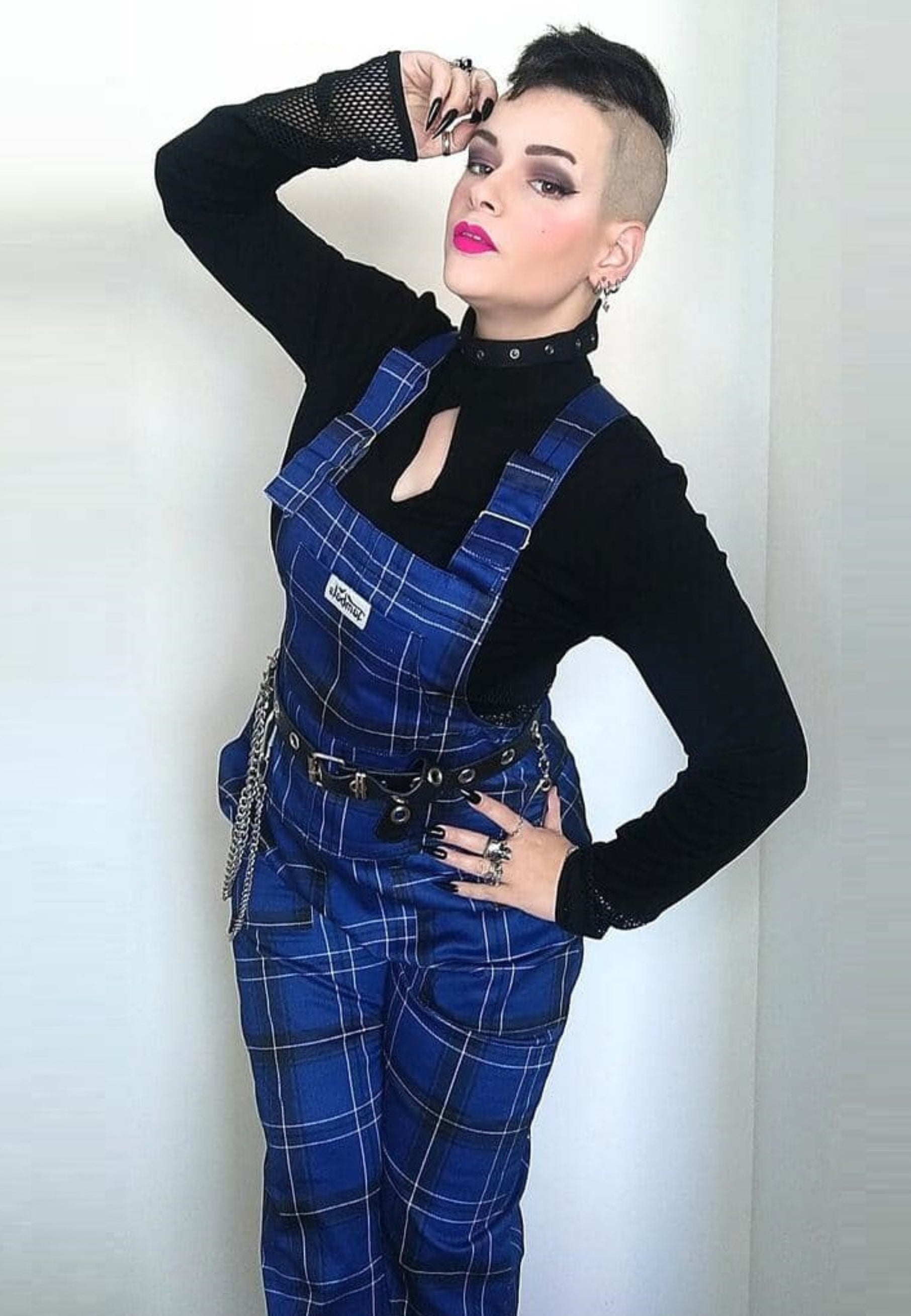 Model in classic dark blue and black tartan dungarees. Studio photo on a plain background