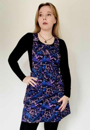 Woman wearing a pinafore with a beautiful print of Corvids, crows and ravens. Studio photo 