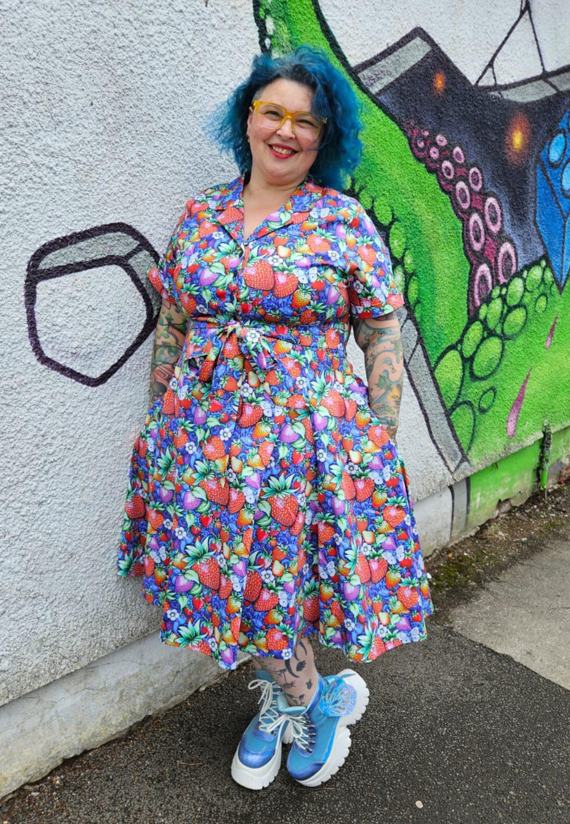Woman wearing Jambats Strawberry Fields retro shirt dress standing next to a graffiti wall and wearing big boots. 