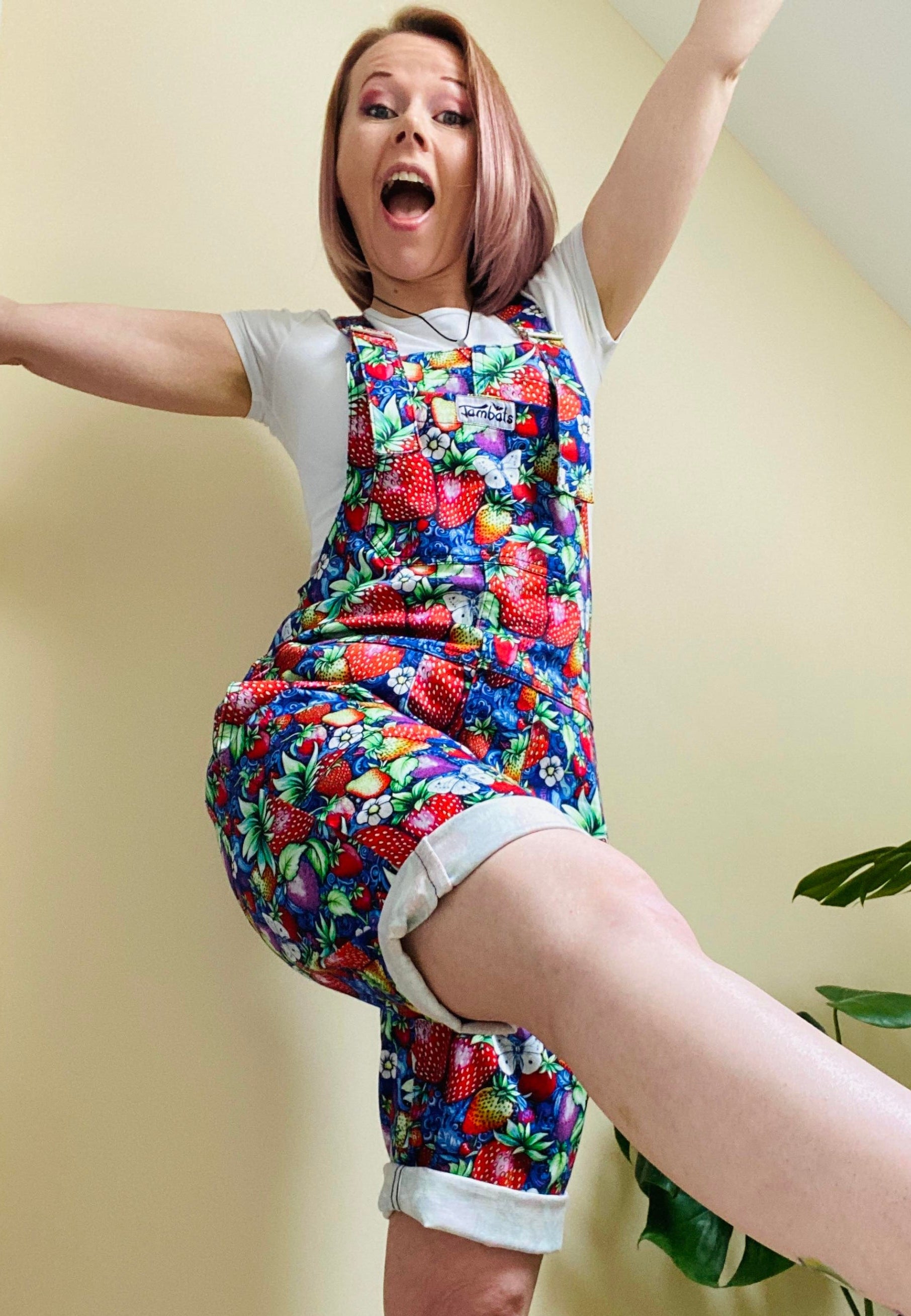 A person wearing a vibrant multicolored floral dungaree shorts with a blue paisley pattern. 