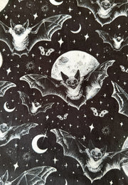 Black fabric with a repeating white and gray print of bats flying around a full moon and stars.