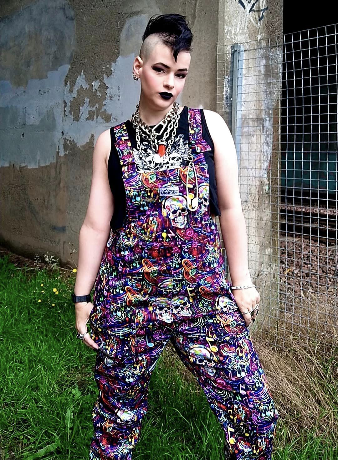 Woman wearing Graffiti Music Skulls Dungarees outdoors in urban setting. Punky vibe. 