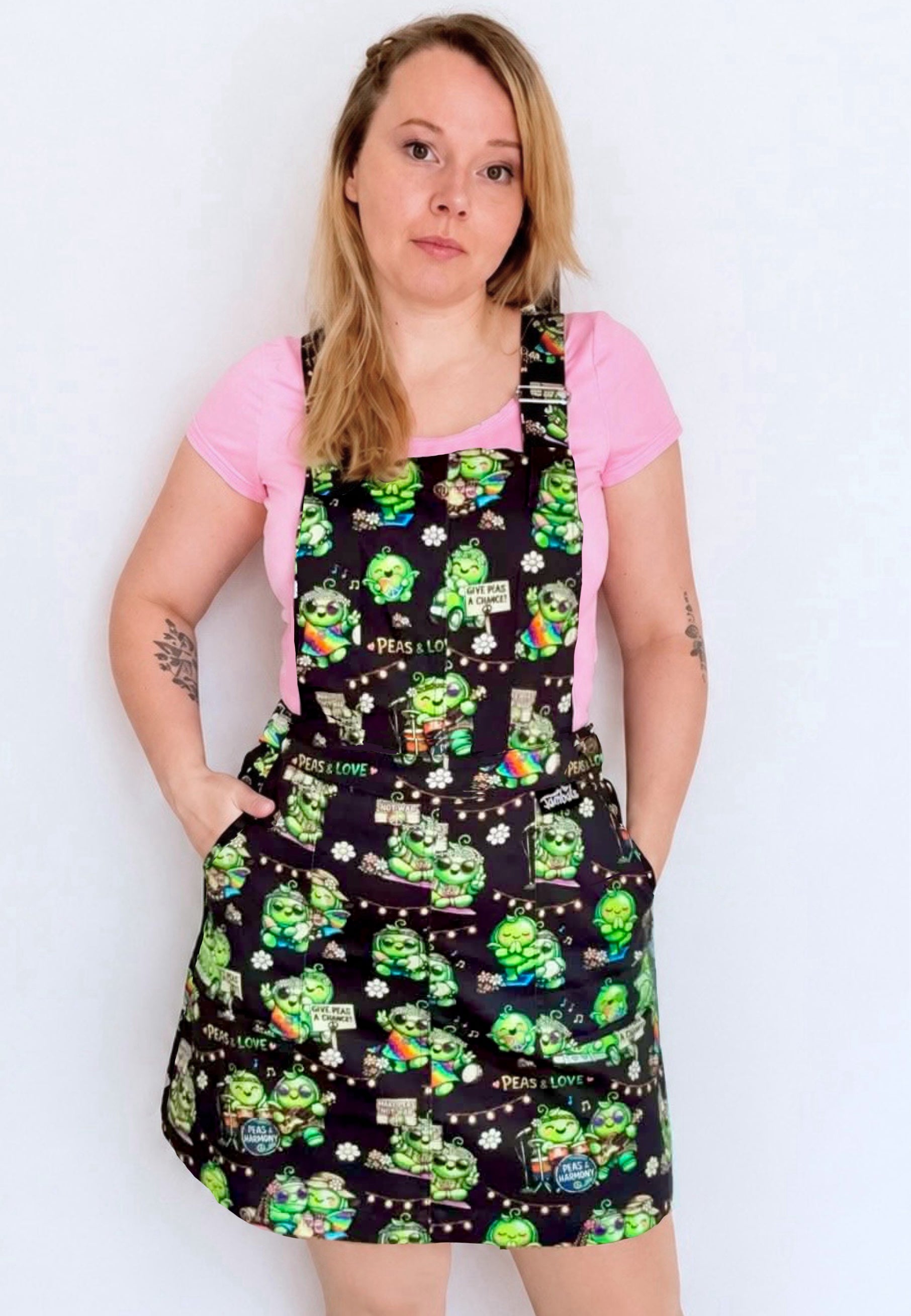 A woman wearing a black pinafore dress with a colourful pattern of hippie peas at a peas and love festival