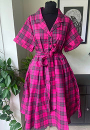 A mannequin wearing a beautiful pink tartan retro shirt dress with a belt and button shirt bodice and full skirt.