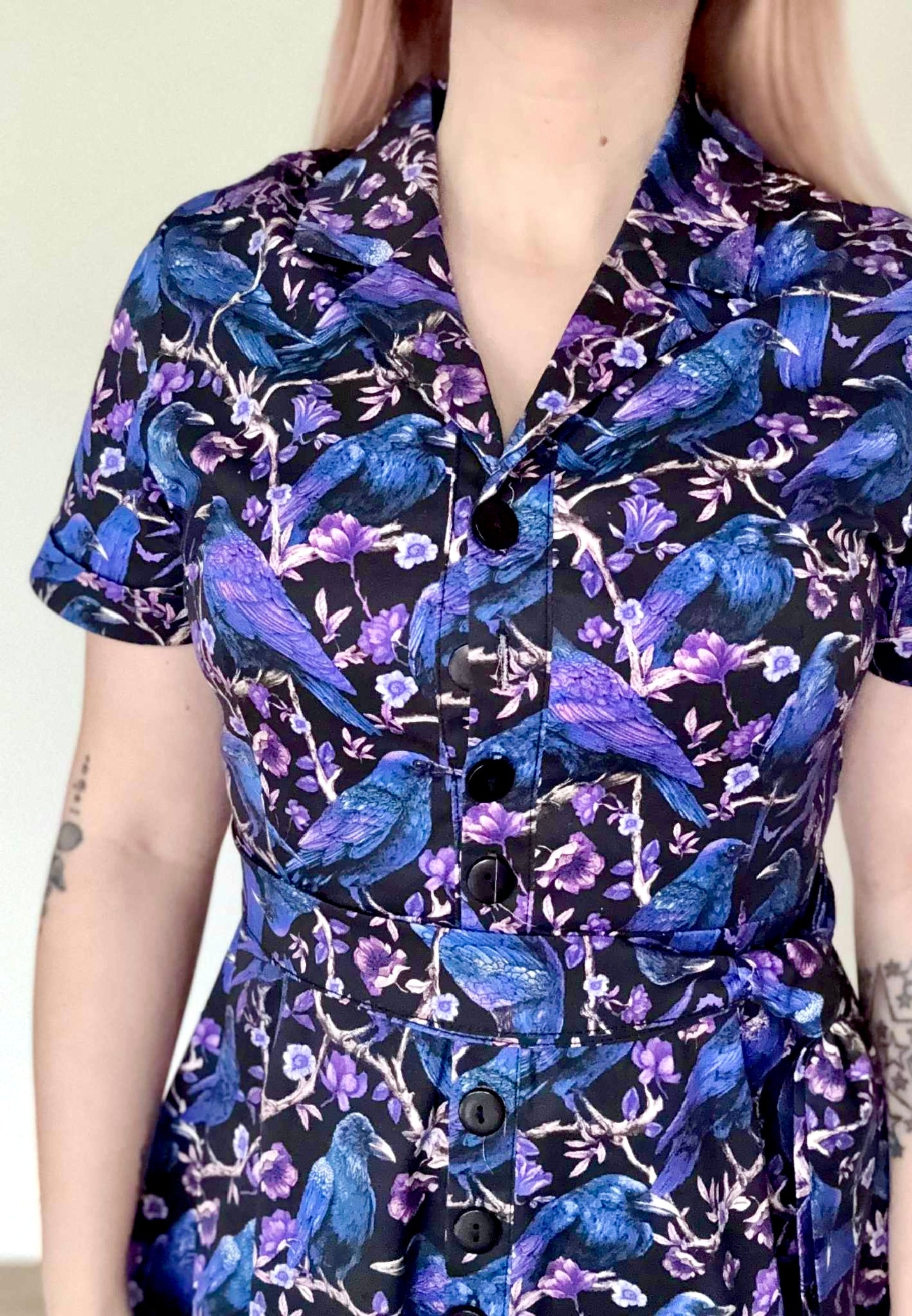 Close up of the beautiful print on the Corvid dress. Dress is black with blue and purple crows and raven perched amongst branches. Soft goth style. 