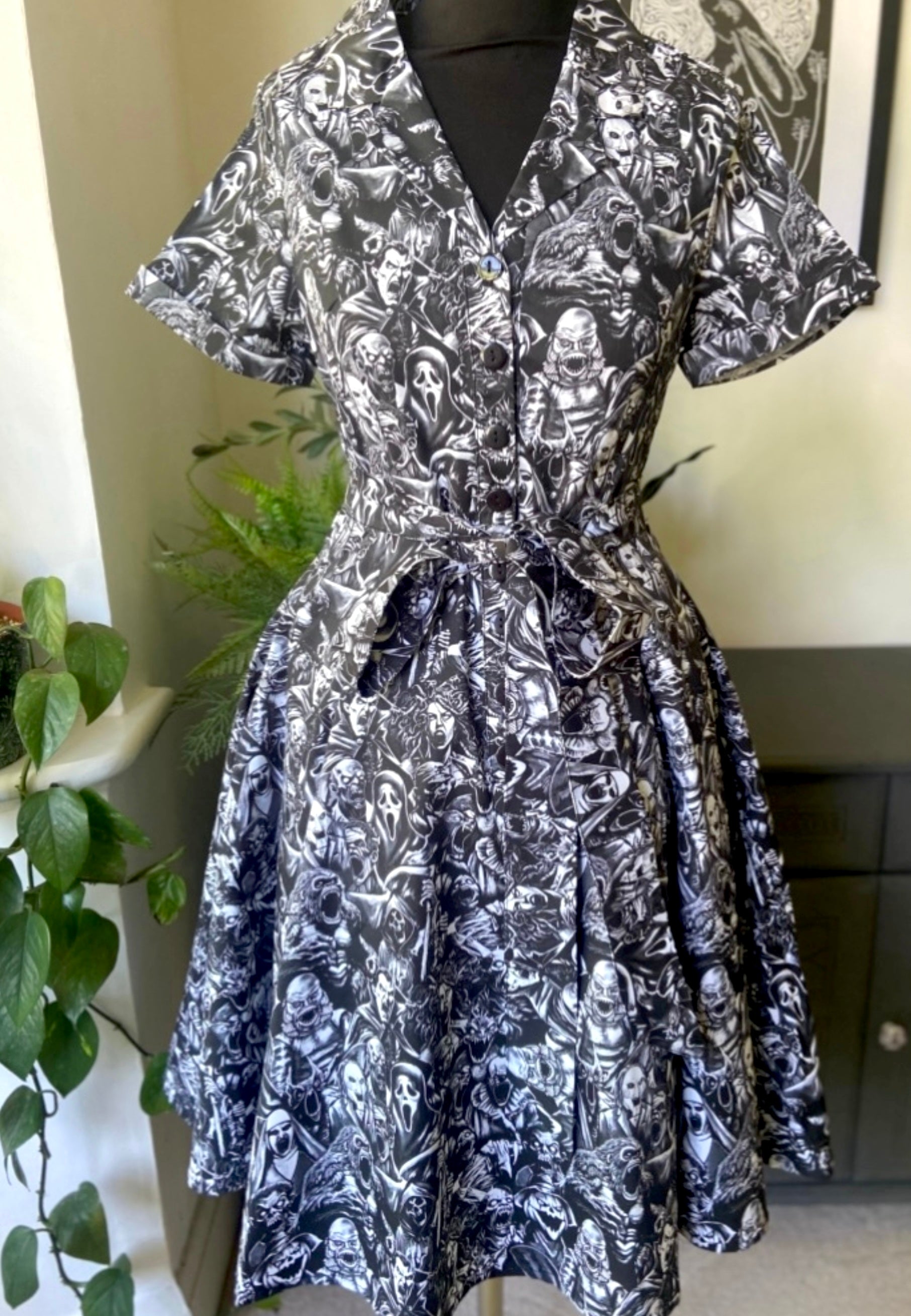 Mannequin photo with  a retro style shirt dress with a gothic print in a grayscale of all the old school monster, cryptoids and zombies all screaming. In the style of the old horror comics. Horror goth style dress.