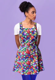 Woman wearing a beautiful pinafore dress with a vibrant wild strawberry print. 