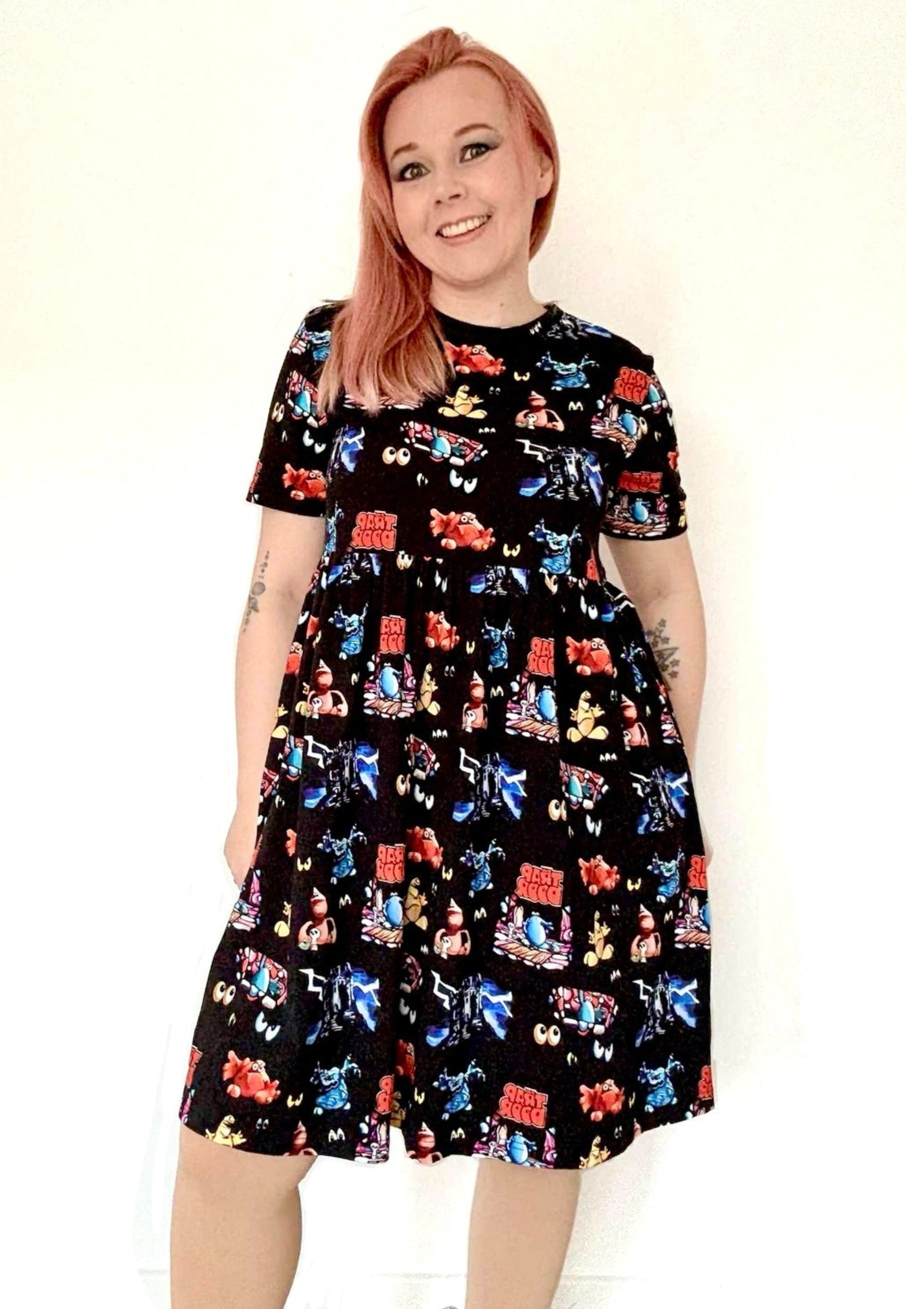 Woman wearing a black dress with a vibrant design of the 1980s children’s tv programme Trap Door
