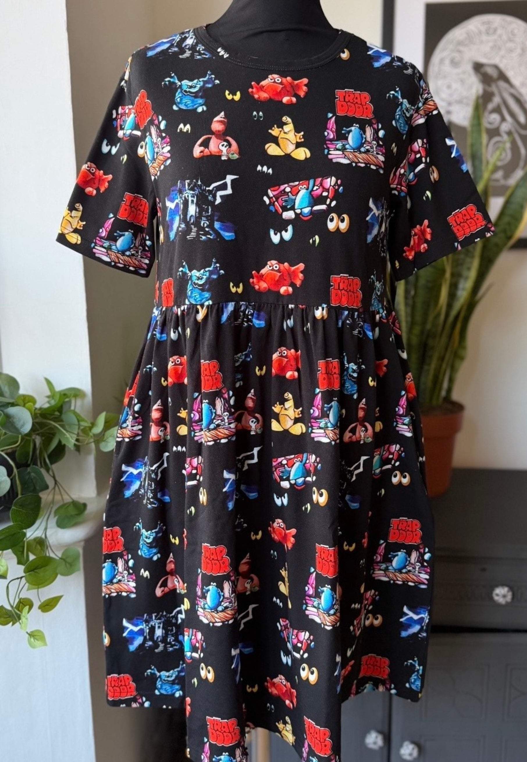 Black dress with colorful Trap Door design on a mannequin against a neutral background