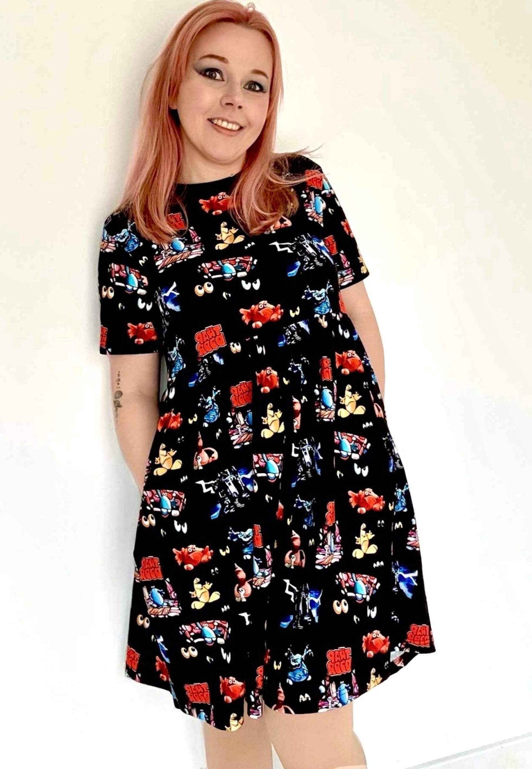 Woman wearing a black dress with a vibrant design of the 1980s children’s tv programme Trap Door