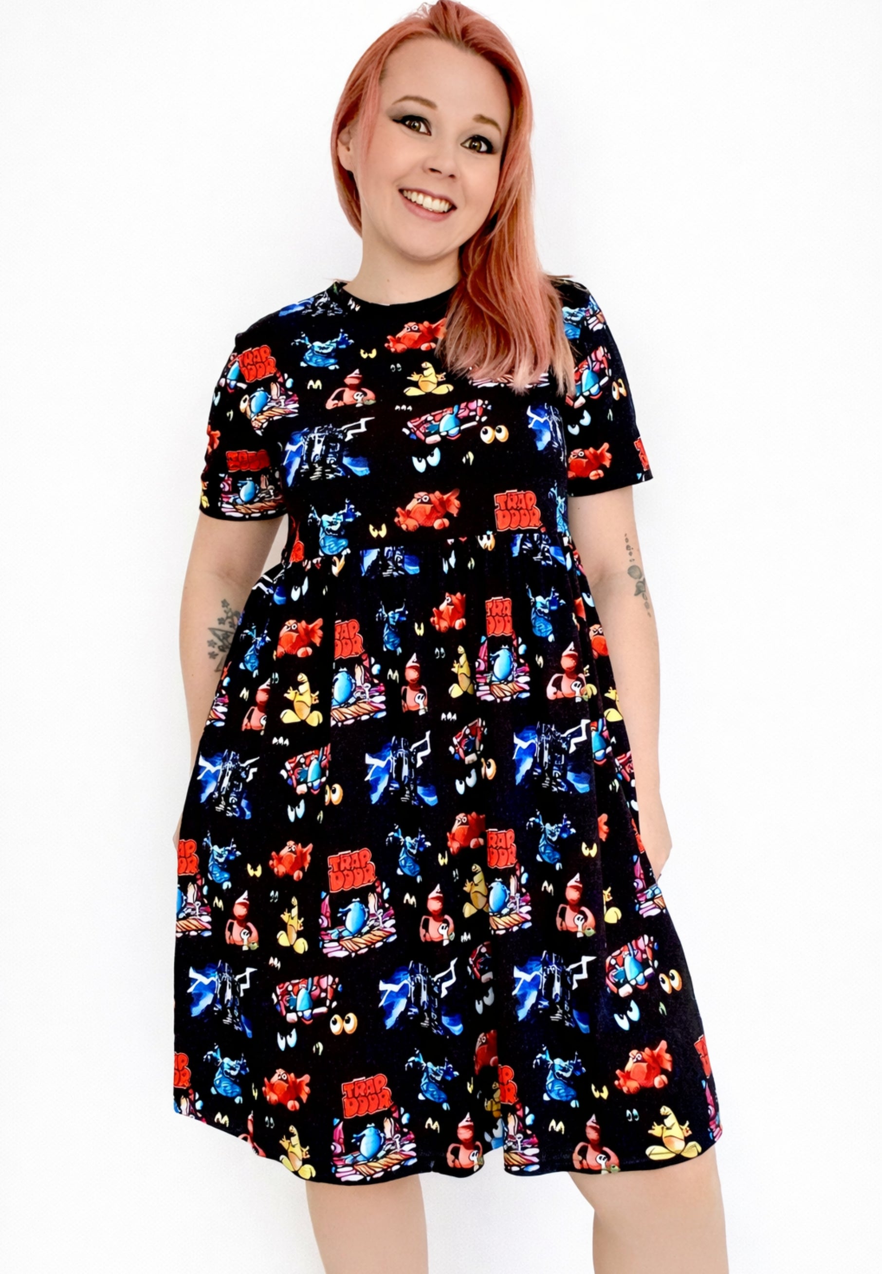 Woman wearing a black dress with a vibrant design of the 1980s children’s tv programme Trap Door. Cult 80s TV Nostalgia