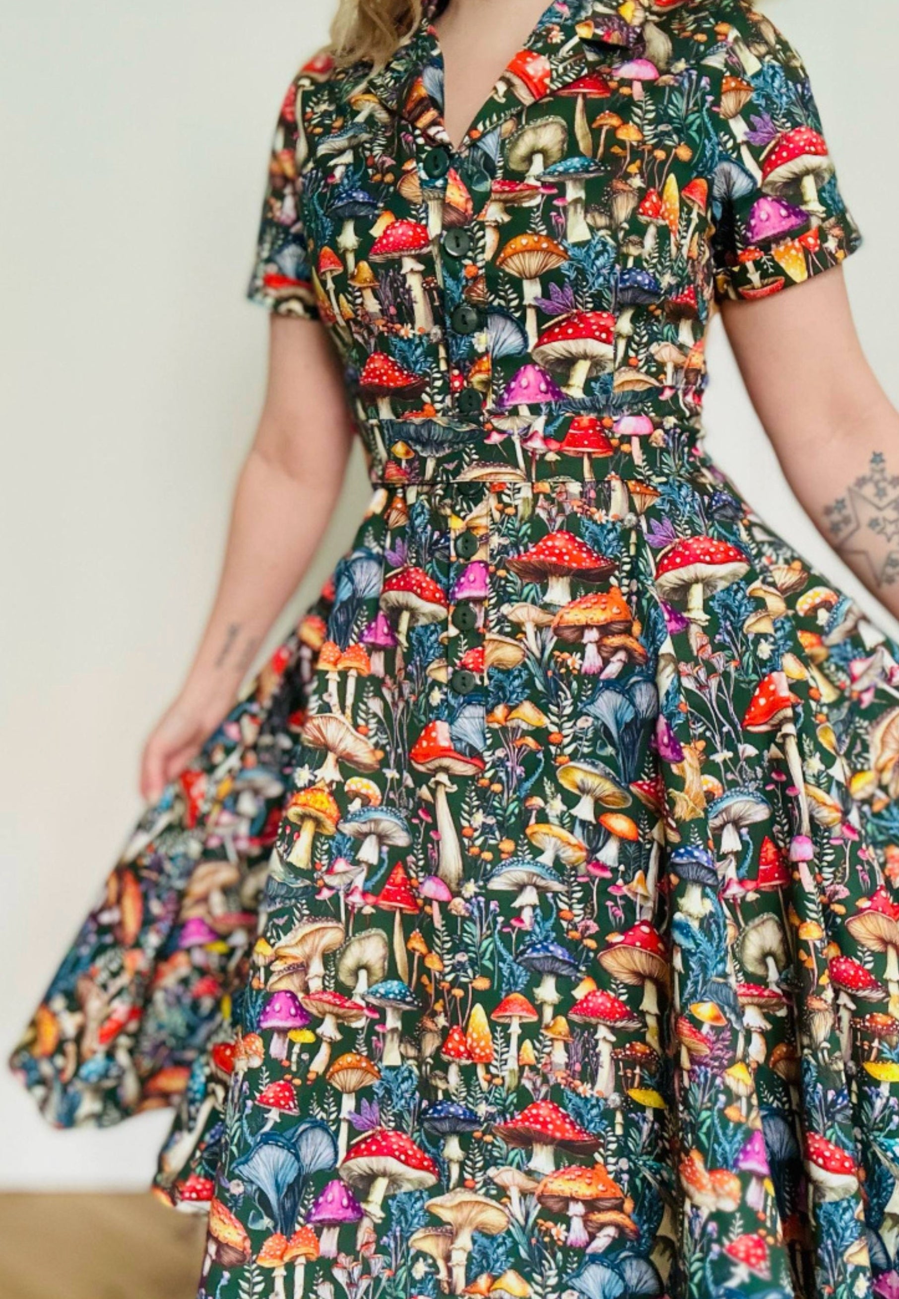 Woman wearing a beautiful  mushroom print dress against a plain background. Full skirted dress. 