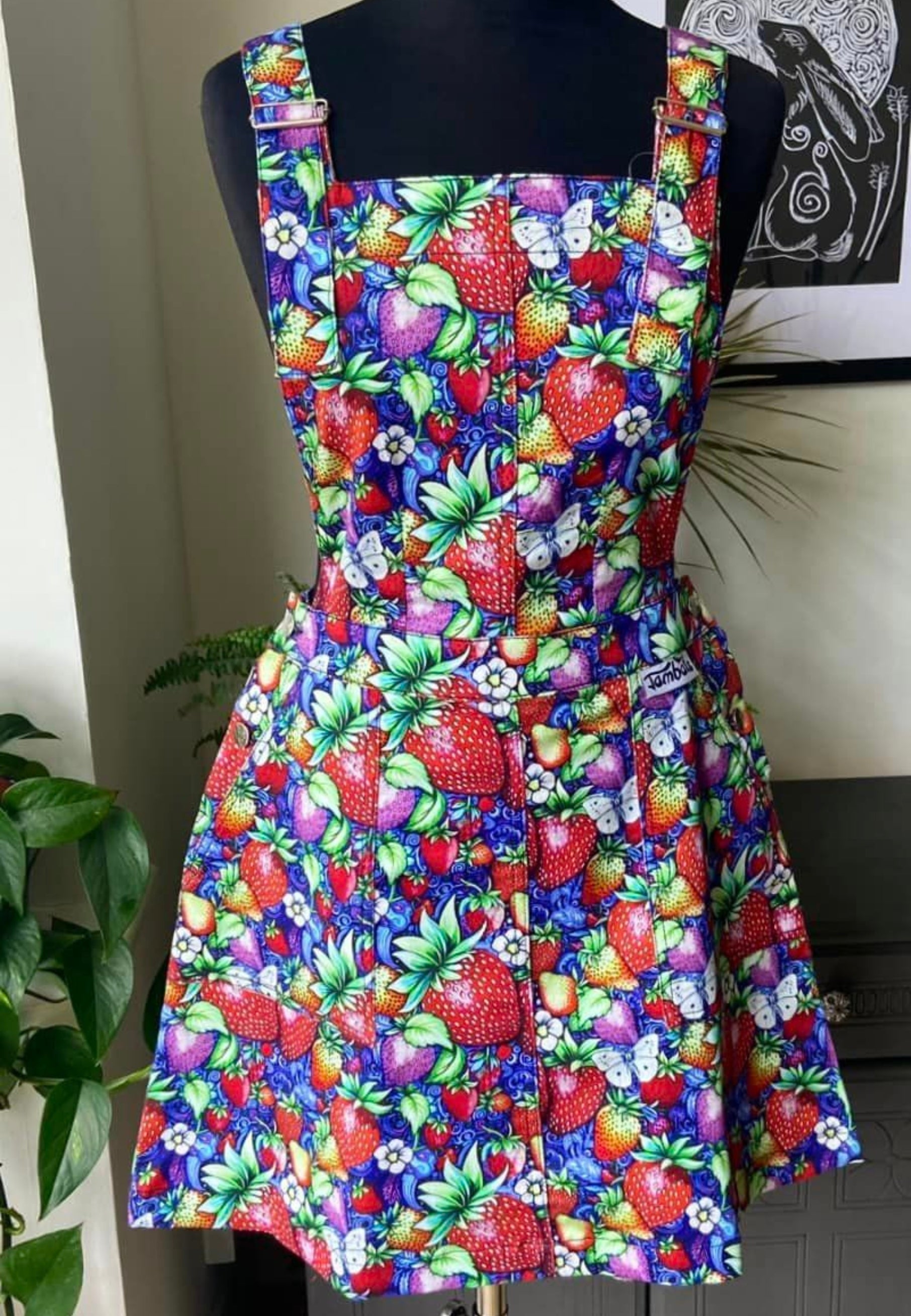 A vibrant Strawberry print pinafore on a mannequin.  