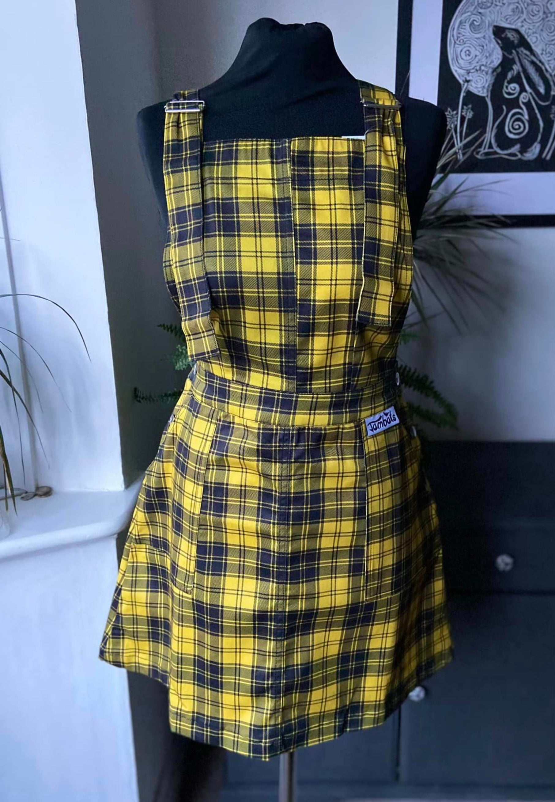 Yellow and black tartan pinafore on a mannequin. 