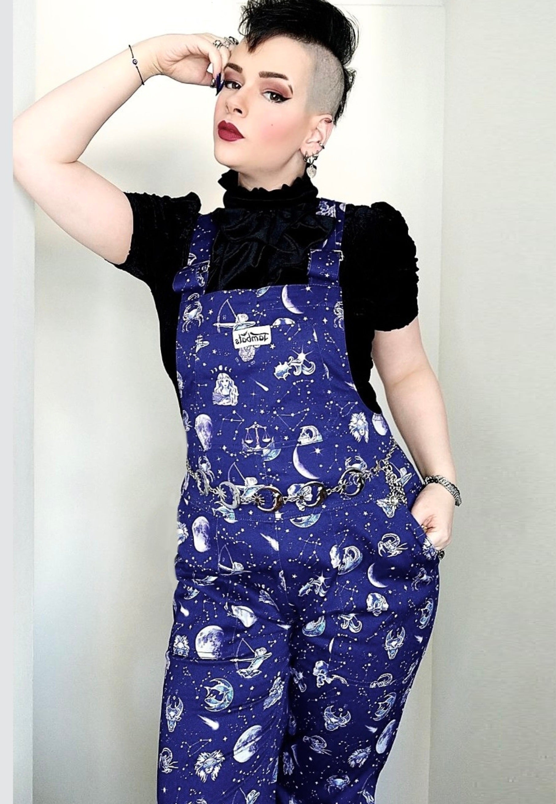 Woman wearing deep
Blue zodiac celestial print dungarees. 